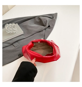 Detail of red leather clutch bag featuring oversized silver studs and magnetic closure