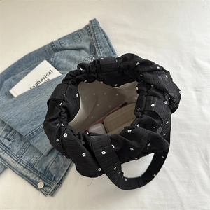 Black floral chiffon bucket bag with daisy print and drawstring showing internal storage
