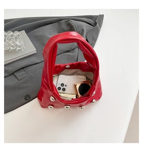 Detail of red puffy handbag showing internal capacity for phone, powder, and silver studs