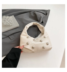 Detail of cream leather shoulder bag with decorative silver spherical metal studs