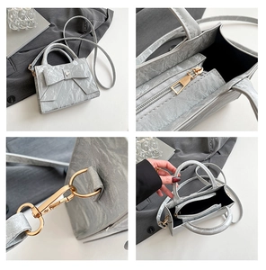 Silver bow handbag details showing smooth zipper, gold hardware, and inner compartments