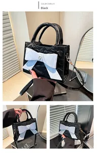 Detail view of black pleated handbag with large white bow and heart-shaped crystal decor