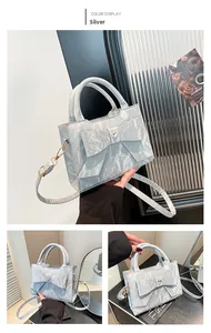 Detail of silver pleated handbag with large bow and heart-shaped rhinestone buckle