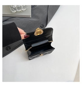 Close-up of black quilted mini bag with golden heart lock and internal compartment