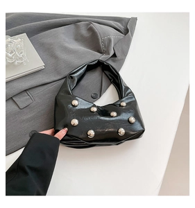 Close-up of black glossy hobo bag with large silver rivets and wrinkled leather texture