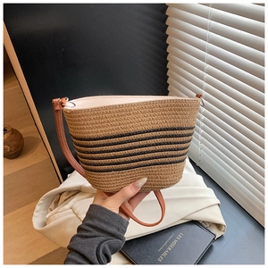 Détail montrant la texture en paille tressée et le motif à rayures noires du sac fourre-tout