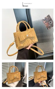 Close-up of brown handbag featuring a large bow and sparkling heart rhinestone detail