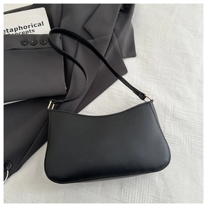 Dettaglio di una borsa hobo minimalista in pelle nera con finiture dorate e tracolla