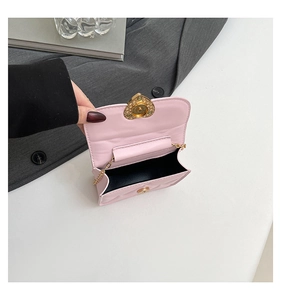 Close-up of pink quilted mini bag with golden heart-shaped clasp and chain strap