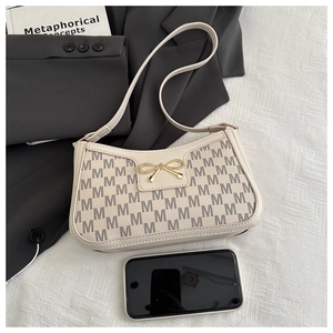 Dettaglio borsa baguette bianco off-white con motivo M e fibbia a fiocco dorata in un set