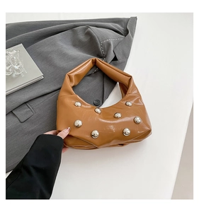 Detail of caramel brown rivet shoulder bag with silver studs and sleek PU leather finish