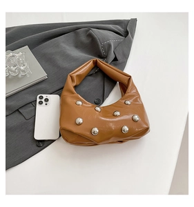 Detail view of brown soft PU leather hobo bag with large silver rivets on grey suit jacket