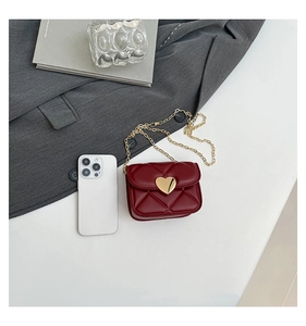 Detail view of red quilted mini bag featuring golden heart buckle and chain strap