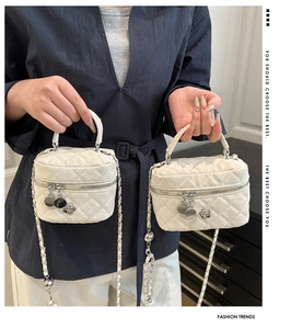 Detailed close-up of white quilted mini bag with silver chain strap and flower charm