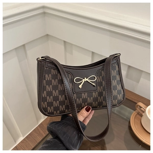 Dettaglio della borsa baguette marrone scuro con fiocco dorato e motivo all-over
