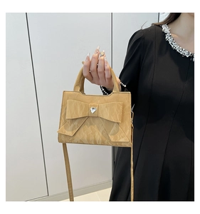 Détail du sac à main marron clair en cuir plissé avec nœud et strass en forme de cœur
