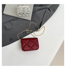 Detail of red quilted mini crossbody bag with gold chain strap and diamond stitching
