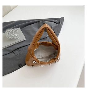 Close-up of caramel leather tote bag showing silver rivet studs and magnetic closure detail