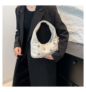 Detail of cream white underarm bag with silver round rivets on soft leather texture