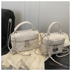 Detail view of white quilted mini bag with gold chain strap and metal bead charm
