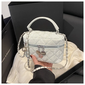 Macro detail of quilted white mini bag with silver chain strap and camellia charm
