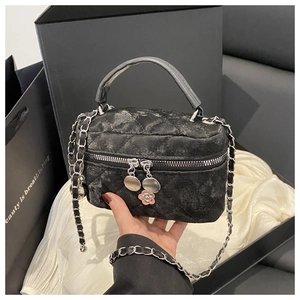 Close-up of quilted black crossbody bag with silver camellia charm and chain strap