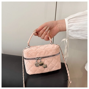 Detail of pink velvet quilted crossbody bag with silver chain and floral zipper charms