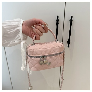 Detailed shot of pink quilted crossbody bag with double zippers and camellia pendant charm