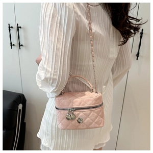 Detail of pink quilted vanity bag with metal flower charm and chain strap on model