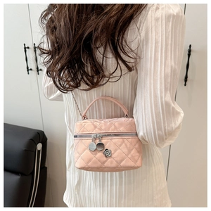 Pink quilted bucket bag with silver chain and flower charm worn with white dress