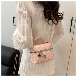 Detailed back view of model wearing a pink quilted vanity bag with gold chain strap