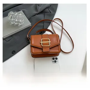 Brown structured faux leather handbag size comparison with a smartphone on desk
