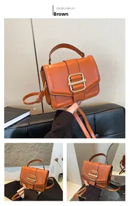 Detail of brown vintage leather handbag showing gold square buckle and adjustable strap