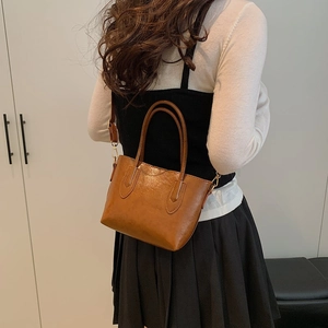 Minimalist brown faux leather tote bag with top handles shown on model back