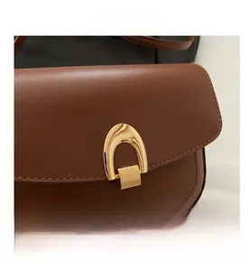 Close-up of a brown leather saddle bag featuring a polished gold horseshoe metal buckle