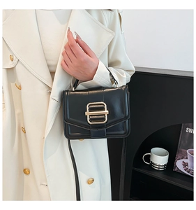 Detail of elegant black leather handbag with gold buckle and top handle in lifestyle setting