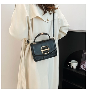 Detail of black minimalist leather handbag with gold buckle and adjustable strap