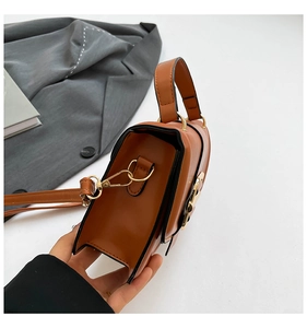Detail view of caramel brown crossbody bag with gold hardware and smooth leather texture