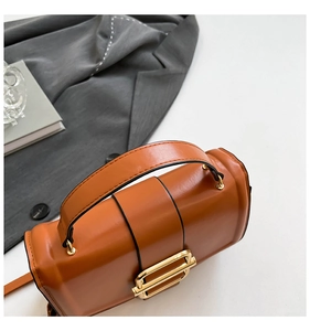 Close-up of brown leather handbag with gold square buckle and black edge finish