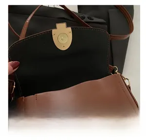 Detail shot of the secure gold magnetic closure on a brown leather crossbody bag
