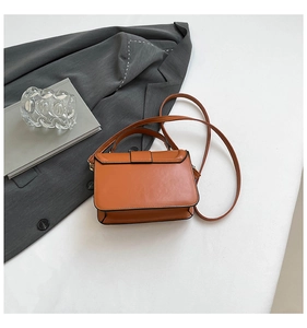 Detailed close-up of brown crossbody bag featuring sleek flap and black edge finish