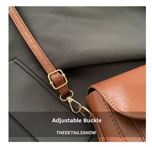 Detail of adjustable leather strap with premium metal buckle on brown saddle bag