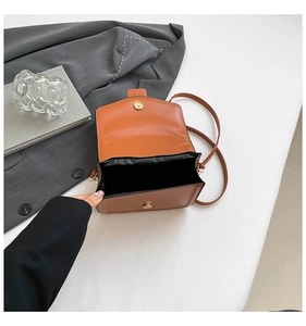 Detail showing the brown crossbody bag with magnetic buckle and interior compartment