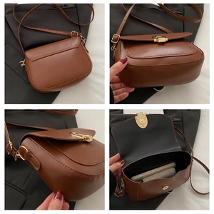 Detail view of caramel brown saddle bag showing gold clasp, adjustable strap and interior
