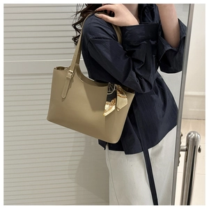 Detail view of khaki bucket bag with decorative silk scarf and gold strap buckle