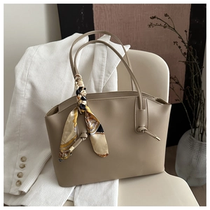 Close-up of beige tote bag with vintage floral scarf on a minimalist chair