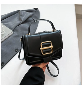 Detailed macro view of black textured leather handbag with a rectangular gold buckle
