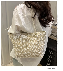 Détail d'un sac cabas tissé beige avec broderie florale et nœud en dentelle délicat