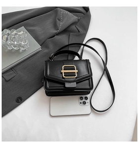 Minimalist black square handbag with gold buckle accent on white studio background