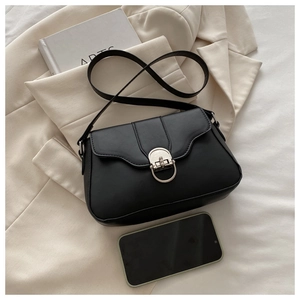 Detail of black leather crossbody bag with metal horseshoe buckle next to a smartphone